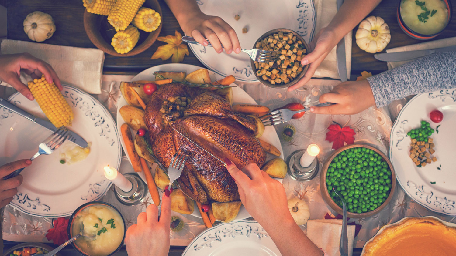 Overhead view of a family celebrating Thanksgiving at the dinner table with a traditional roasted turkey with side dishes