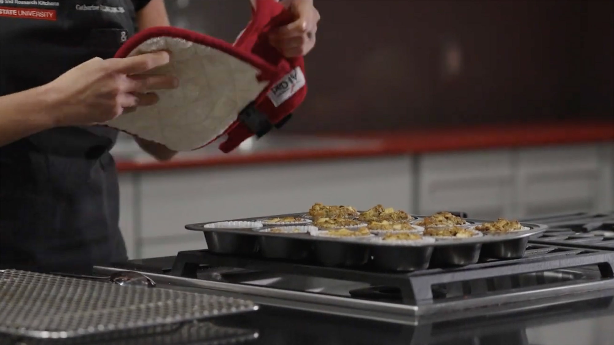 A baking tray full of freshly baked banana nut med muffins sitting on a stove top.